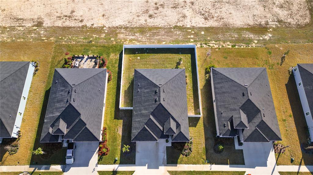 An aerial view shows three suburban houses with dark shingled roofs and fenced backyards — 9191 SW 57TH TERRACE, OCALA, FL