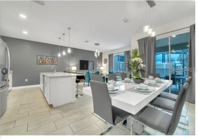 A modern open-concept kitchen and dining area with gray walls, white cabinetry, and tile flooring — 4983 WINDERMERE AVENUE, KISSIMMEE, FL