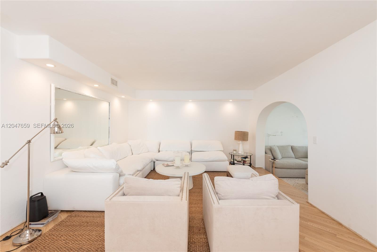 A living room features a large white sectional sofa, two armchairs, and an arched doorway — 9940 Collins Ave # 10, Bal Harbour FL 33154, BAL HARBOUR, FL