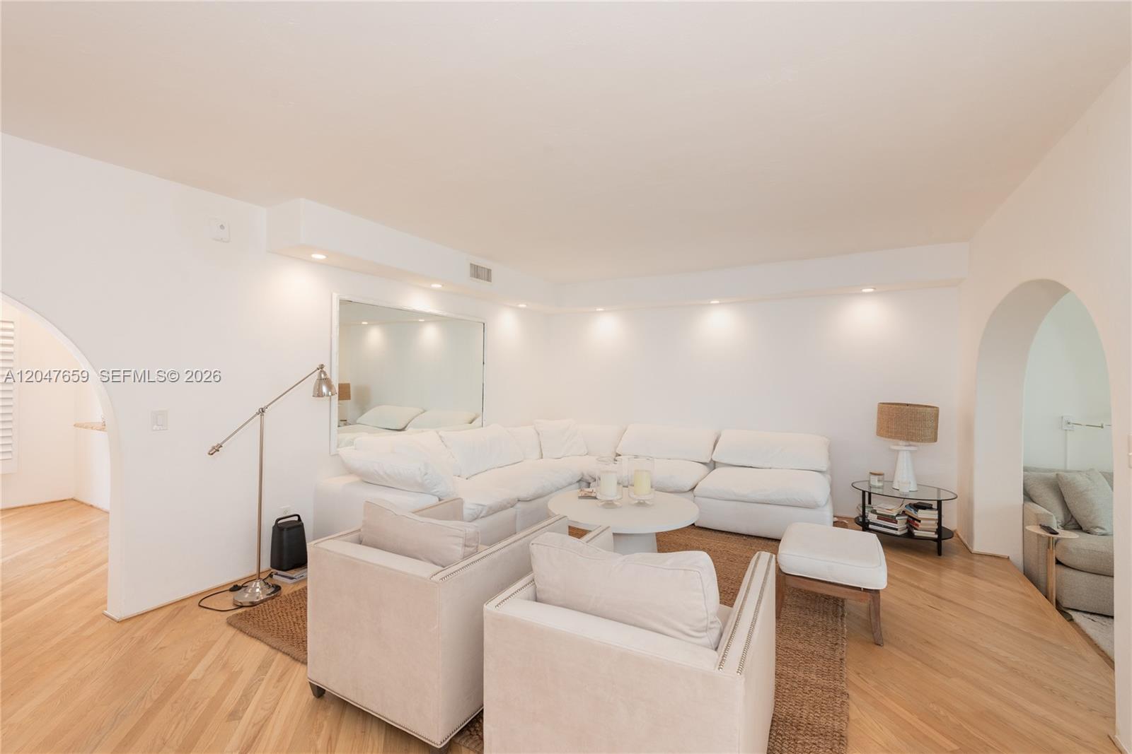 A living room features a white sectional sofa, two armchairs, and arched doorways — 9940 Collins Ave # 10, Bal Harbour FL 33154, BAL HARBOUR, FL