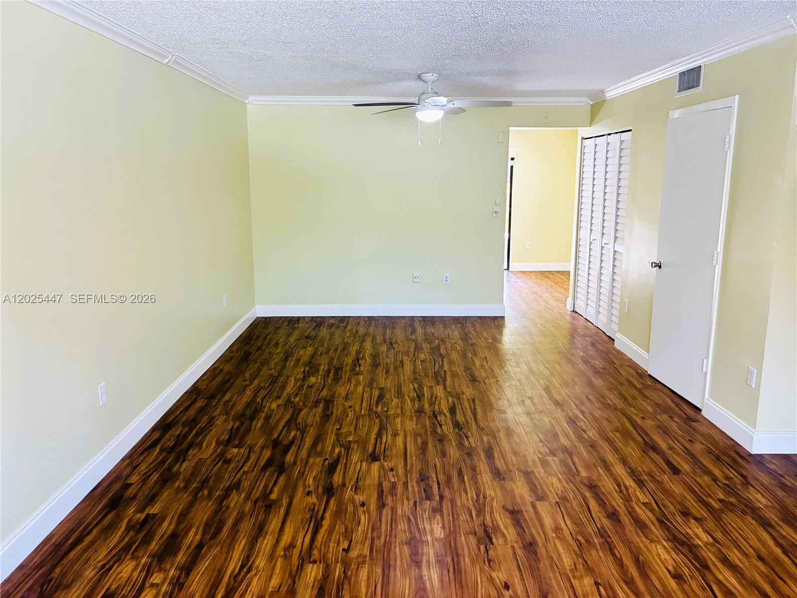 An empty room features light yellow walls, dark wood-look flooring, and a ceiling fan — 7796 SW 102nd Ln, Miami FL 33156, MIAMI, FL