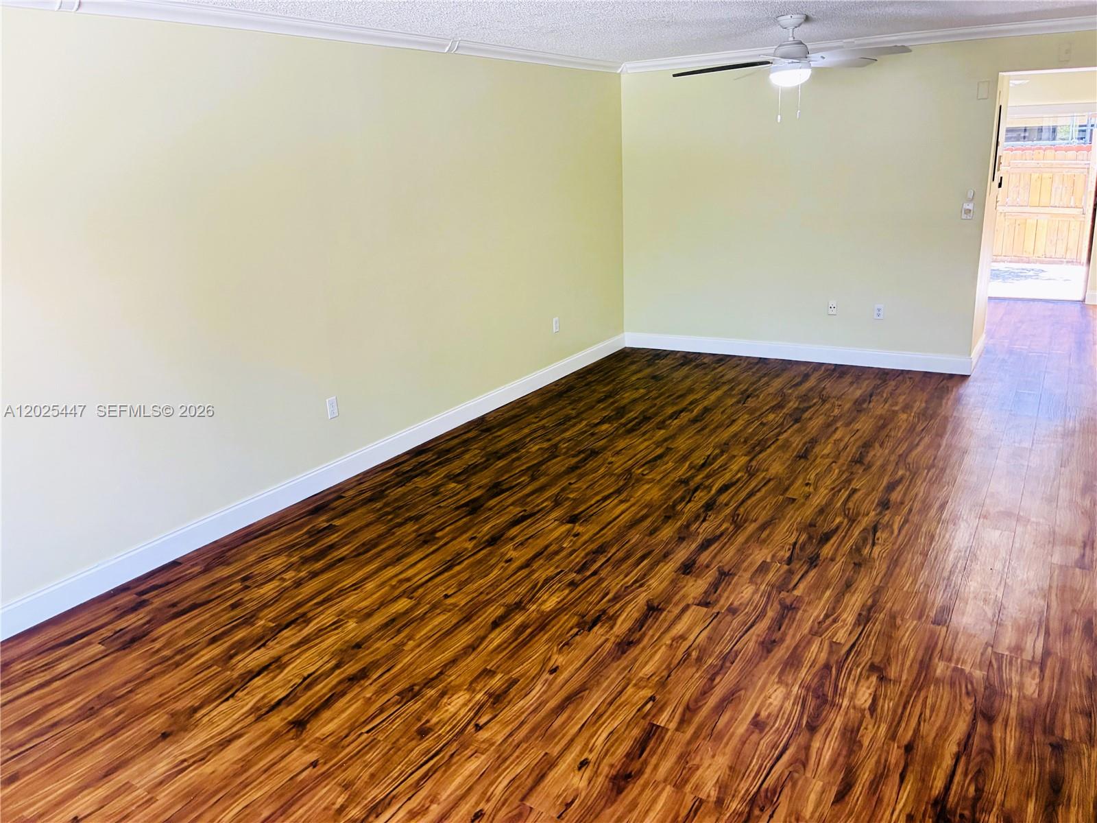 An empty room features light yellow walls, dark wood-look flooring, and a ceiling fan — 7796 SW 102nd Ln, Miami FL 33156, MIAMI, FL