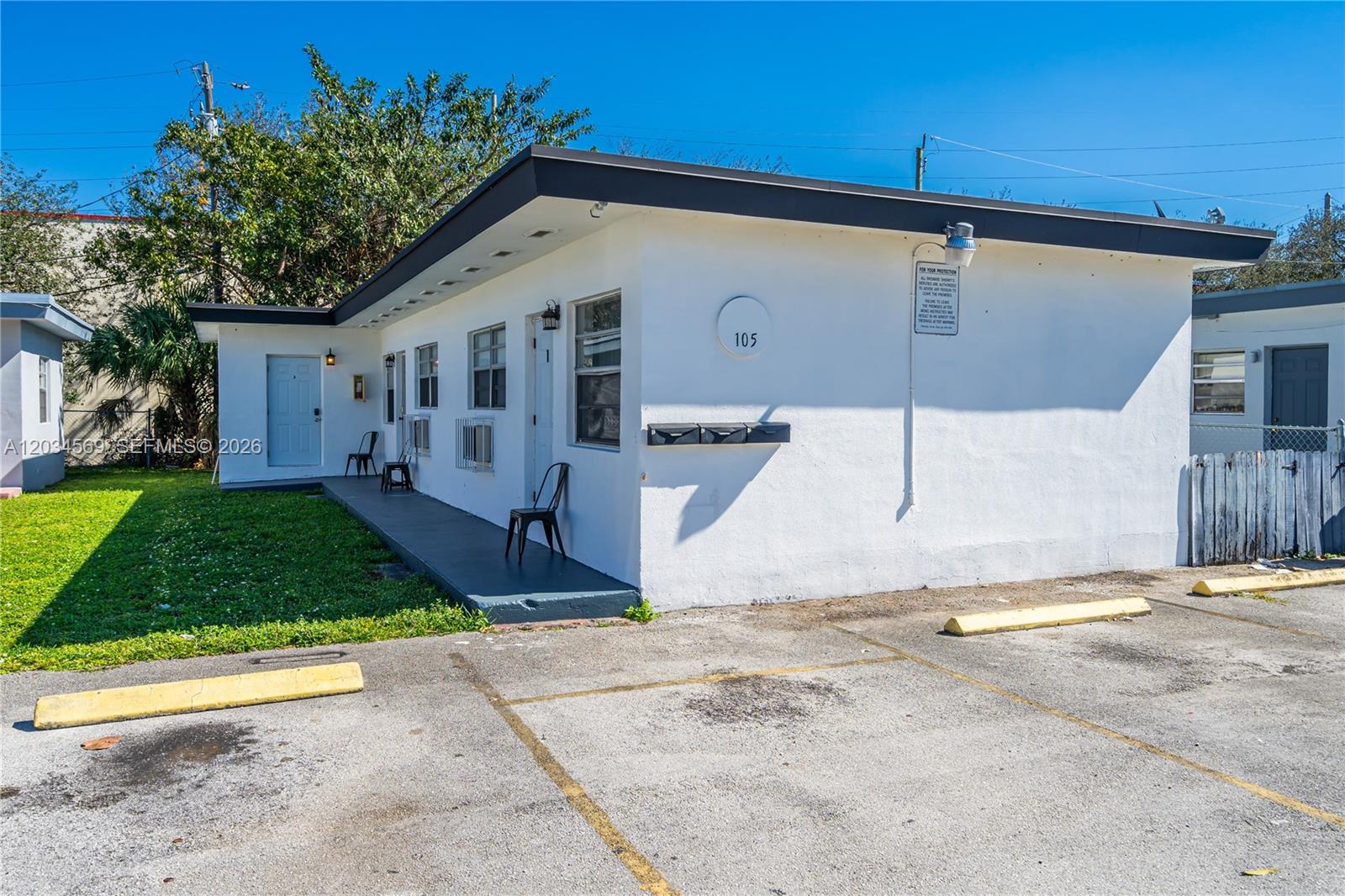 A single-story white building with a flat roof, a small porch, and an asphalt parking lot — 105 SW 5th Ct, Dania Beach FL 33004, DANIA BEACH, FL