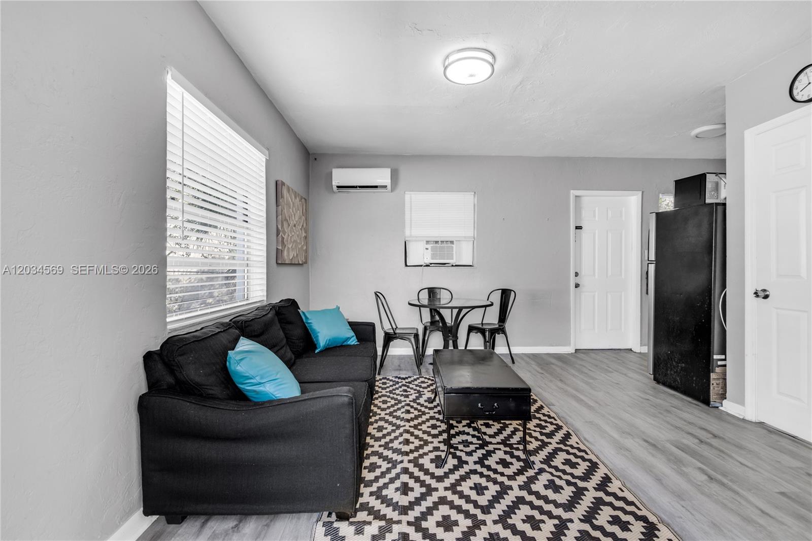 A living room features a black sofa, a dining set, and gray flooring — 105 SW 5th Ct, Dania Beach FL 33004, DANIA BEACH, FL