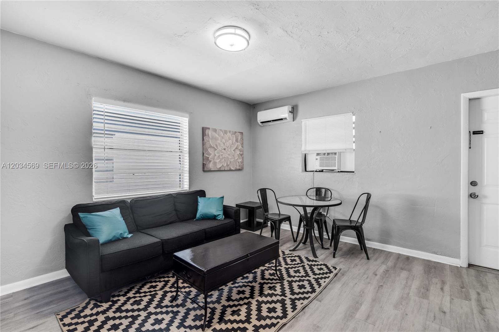 A living room features a black sofa, a dining set, and gray flooring — 105 SW 5th Ct, Dania Beach FL 33004, DANIA BEACH, FL
