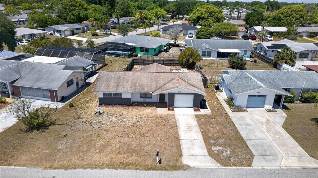 An aerial view shows a single-story house with a driveway and a fenced backyard — 7523 BRIARWOOD DRIVE, PORT RICHEY, FL