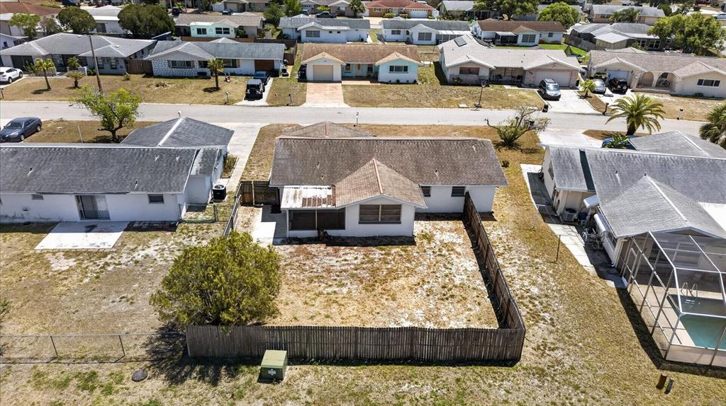 An aerial view shows a single-story house with a fenced backyard and a screened porch — 7523 BRIARWOOD DRIVE, PORT RICHEY, FL