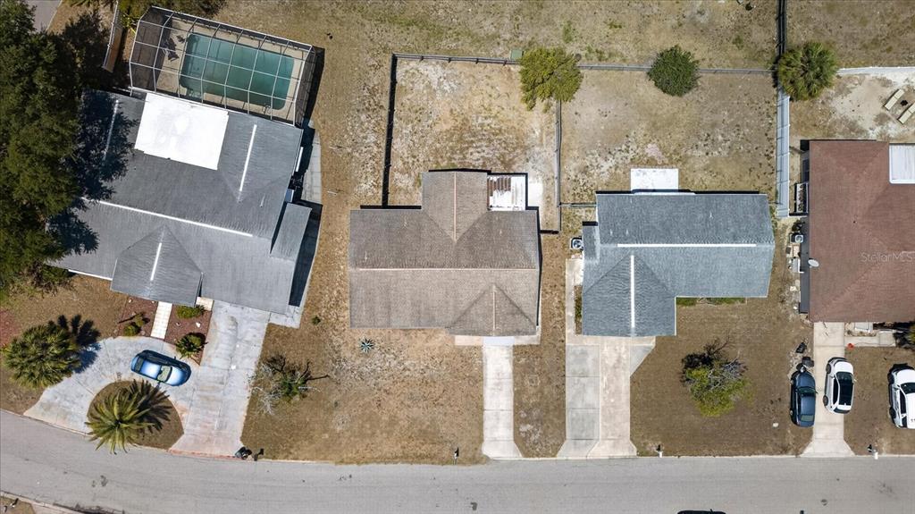 An aerial view shows three suburban houses with driveways and yards along a curved street — 7523 BRIARWOOD DRIVE, PORT RICHEY, FL