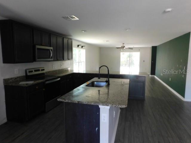A kitchen features dark cabinets, granite countertops, a center island, and dark wood-look flooring — 2350 FIREBRAND ROAD, NORTH PORT, FL