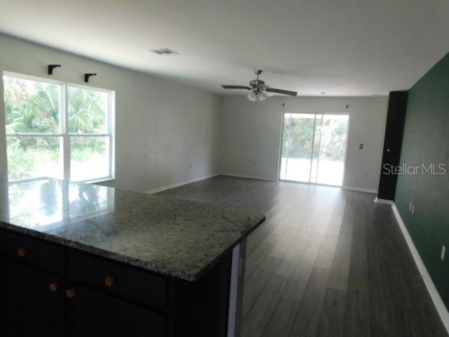 An open-concept living area features dark cabinets, a granite countertop, and wood-look flooring — 2350 FIREBRAND ROAD, NORTH PORT, FL