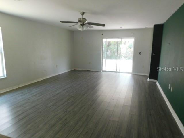 A spacious living room features gray wood-look flooring, a ceiling fan, and sliding glass doors — 2350 FIREBRAND ROAD, NORTH PORT, FL