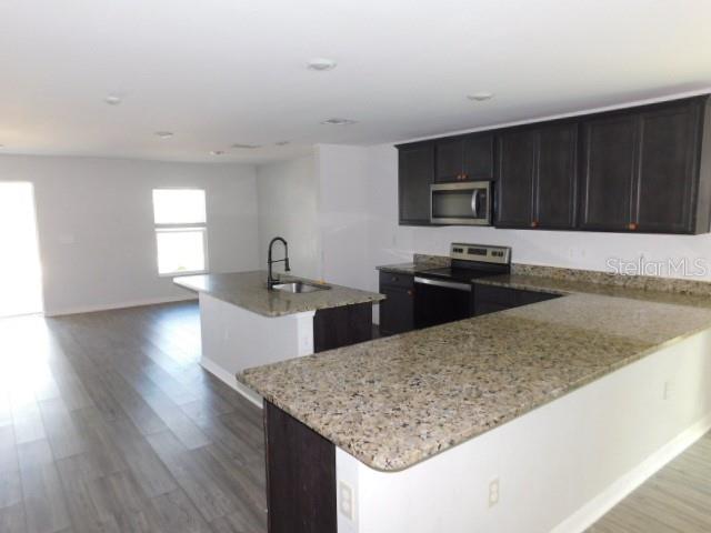A kitchen features dark cabinets, granite countertops, a kitchen island, and light wood-look flooring — 2350 FIREBRAND ROAD, NORTH PORT, FL