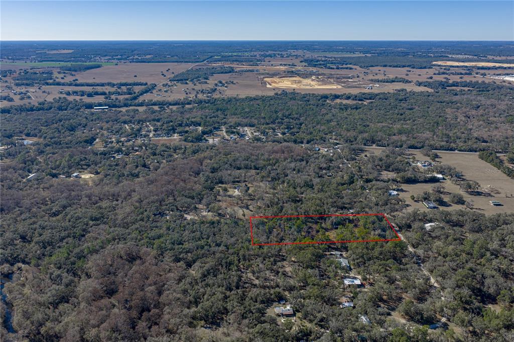 An aerial view shows a rectangular plot of land outlined in red amidst a wooded area — 0 ROWNTREE DRIVE, DADE CITY, FL