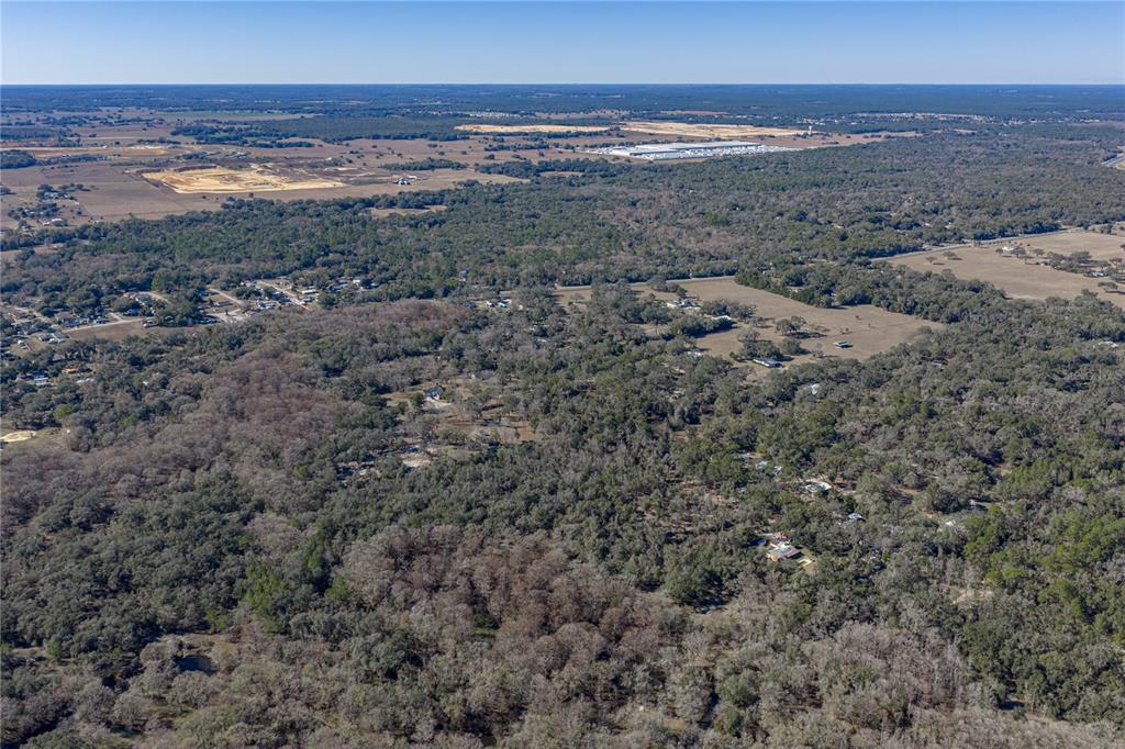 An aerial view shows a rural landscape with scattered houses surrounded by dense forest — 0 ROWNTREE DRIVE, DADE CITY, FL