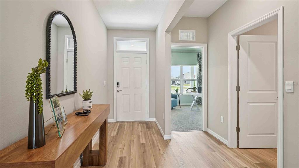 A bright entryway features wood-look flooring, a console table with a mirror, and a doorway — 24274 NW 13TH BOULEVARD, NEWBERRY, FL