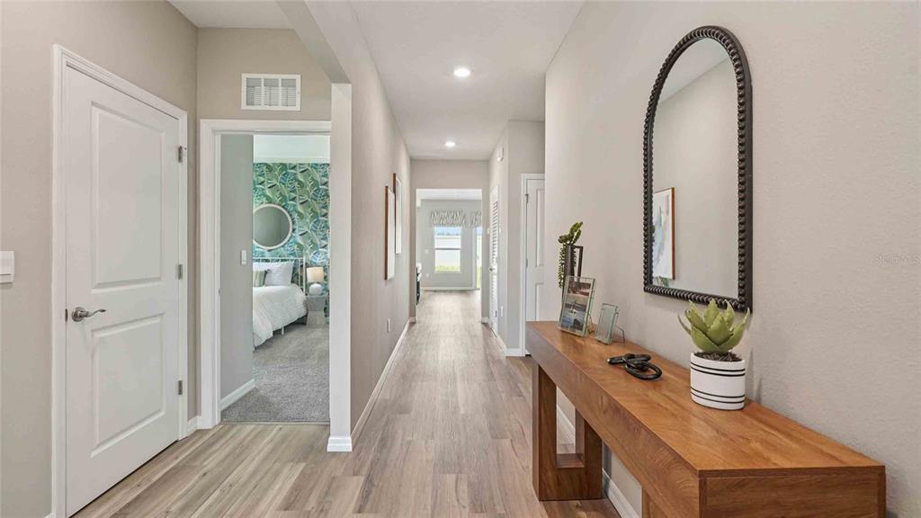 A hallway features light wood-look flooring, a wooden console table, and an arched wall mirror — 24274 NW 13TH BOULEVARD, NEWBERRY, FL