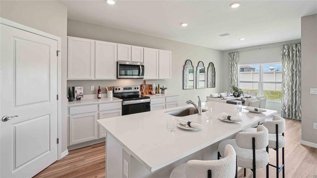 A modern kitchen features white cabinets, a large quartz island, and an adjacent dining area — 24274 NW 13TH BOULEVARD, NEWBERRY, FL