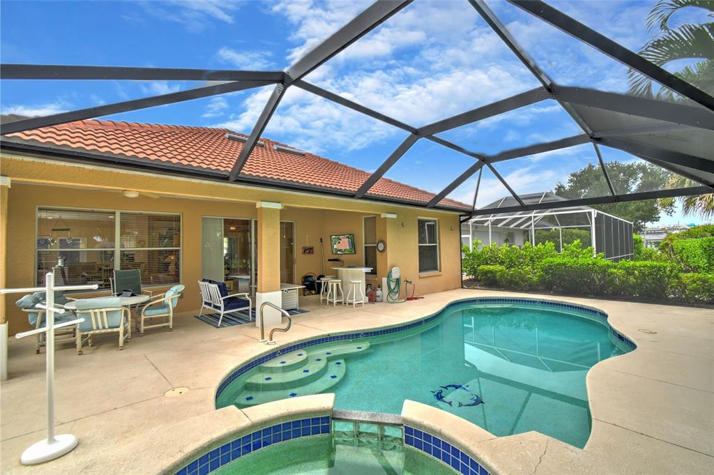 A backyard patio features a swimming pool, a spa, and a screened-in enclosure — 17899 COURTSIDE LANDINGS CIRCLE, PUNTA GORDA, FL