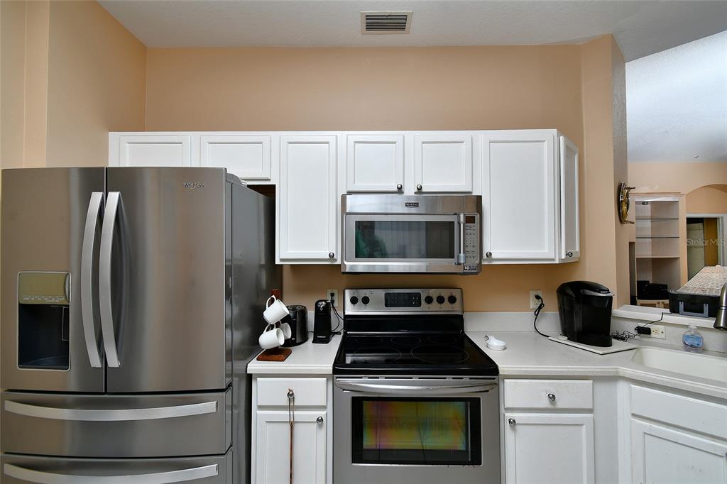 A kitchen features white cabinets, stainless steel appliances, and light-colored countertops — 17899 COURTSIDE LANDINGS CIRCLE, PUNTA GORDA, FL