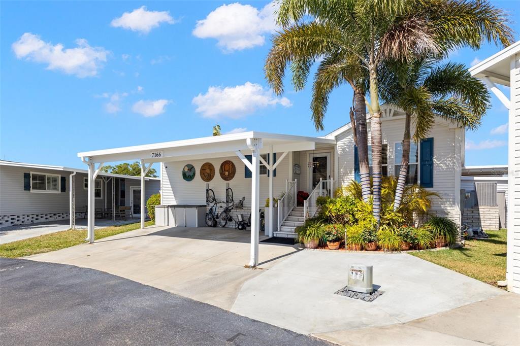 A single-story manufactured home features a white carport, a palm tree, and a concrete driveway — 7166 MOUNT ARLINGTON DRIVE NE UNIT 418, ST PETERSBURG, FL