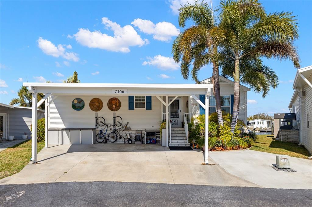 A white mobile home with a carport, palm tree, and three circular wall decorations — 7166 MOUNT ARLINGTON DRIVE NE UNIT 418, ST PETERSBURG, FL