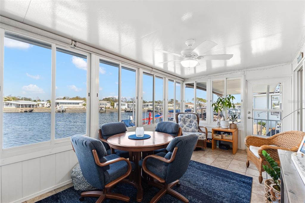 A sunroom with tile floors, a dining set, and large windows overlooking a canal — 7166 MOUNT ARLINGTON DRIVE NE UNIT 418, ST PETERSBURG, FL