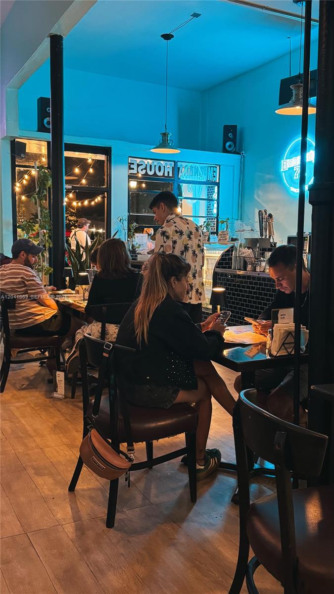 People sit at tables in a dimly lit restaurant with blue accent lighting — 1014 71st St, Miami Beach FL 33141, MIAMI BEACH, FL