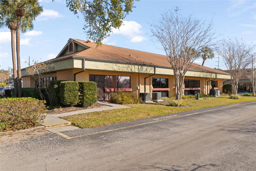 A single-story commercial building with a tan stucco exterior and a brown shingled roof — 2339 SUNSET POINT ROAD UNIT C300-C302, CLEARWATER, FL