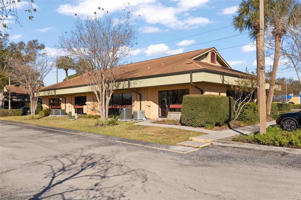 A single-story commercial building with a tan stucco exterior and a brown shingled roof — 2339 SUNSET POINT ROAD UNIT C300-C302, CLEARWATER, FL