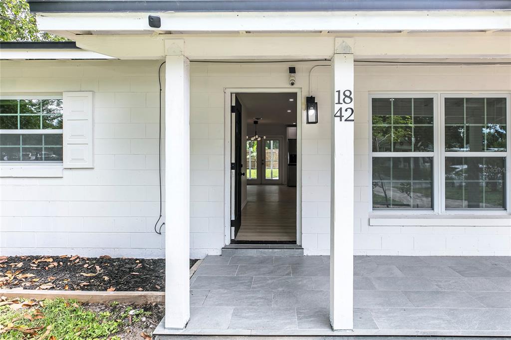 The exterior of a white house features a covered porch with gray tile flooring — 1842 PURITAN AVENUE, WINTER PARK, FL