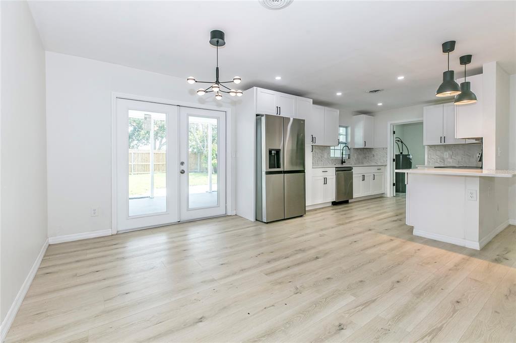 A bright kitchen and dining area features white cabinets, stainless steel appliances, and light flooring — 1842 PURITAN AVENUE, WINTER PARK, FL