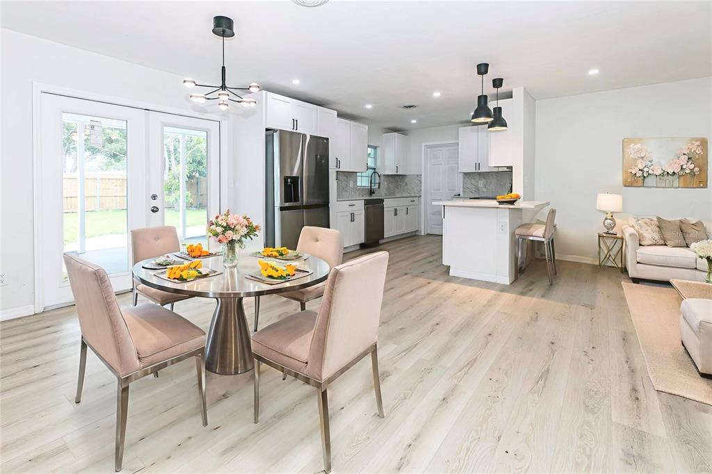 An open-concept kitchen and dining area features white cabinetry, stainless steel appliances, and light flooring — 1842 PURITAN AVENUE, WINTER PARK, FL