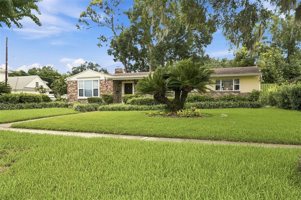 A single-story house with a brick facade, yellow siding, and a large sago palm tree — 1228 SPRING LAKE DRIVE, ORLANDO, FL