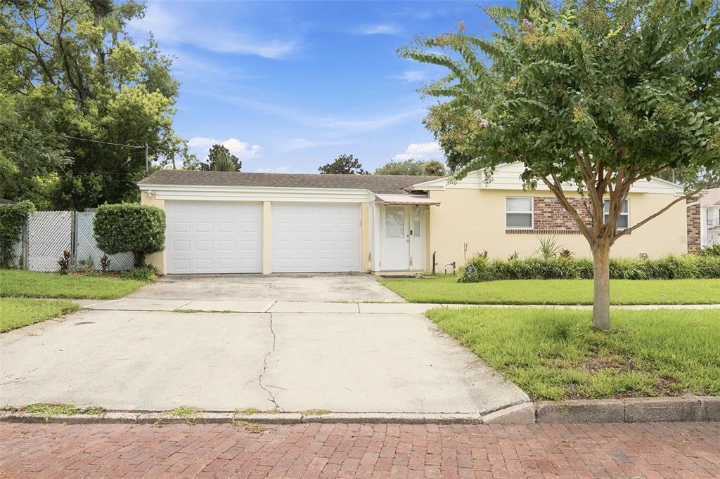 A single-story yellow house with a two-car garage and a concrete driveway — 1228 SPRING LAKE DRIVE, ORLANDO, FL