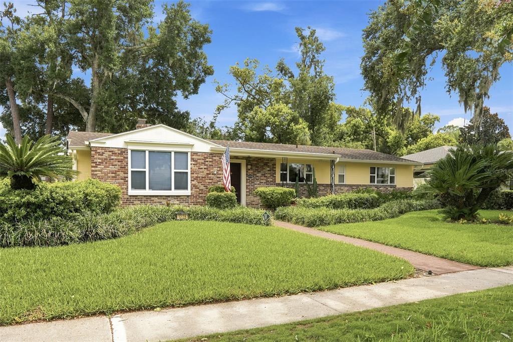 A single-story house with yellow siding, a brick facade, and a front lawn with trees — 1228 SPRING LAKE DRIVE, ORLANDO, FL