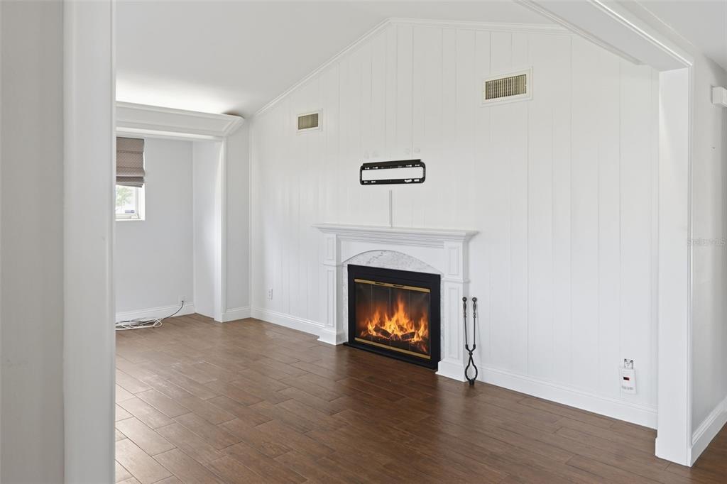 A living room features white vertical paneling, a fireplace with a mantel, and wood flooring — 1228 SPRING LAKE DRIVE, ORLANDO, FL