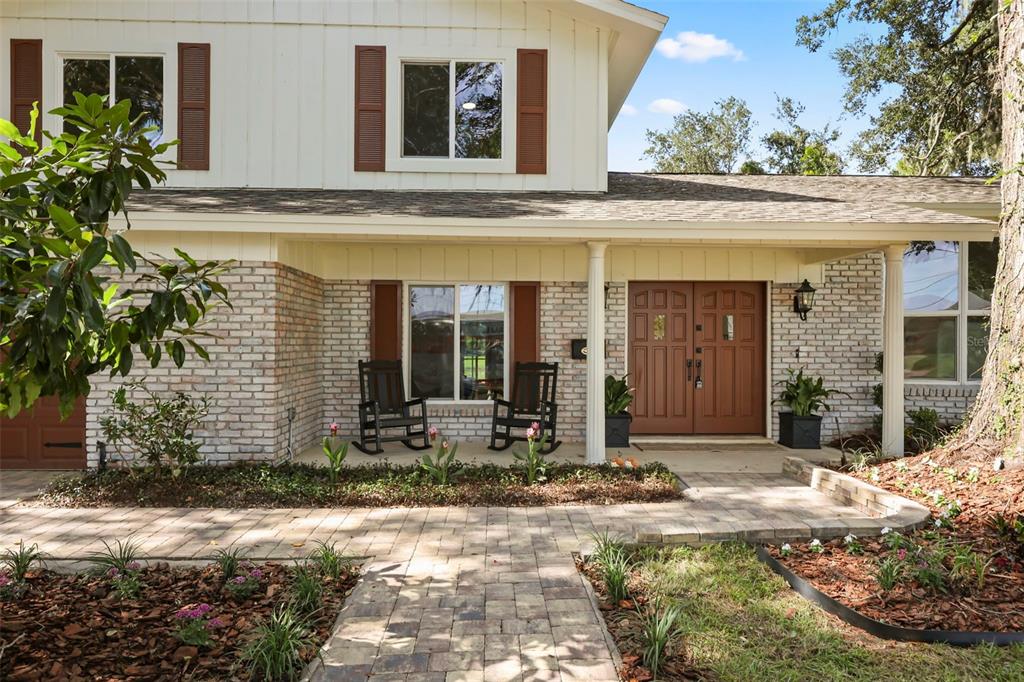 A two-story house with a brick facade, brown shutters, and a paved walkway to the entrance — 1301 DRUID ISLE ROAD, MAITLAND, FL