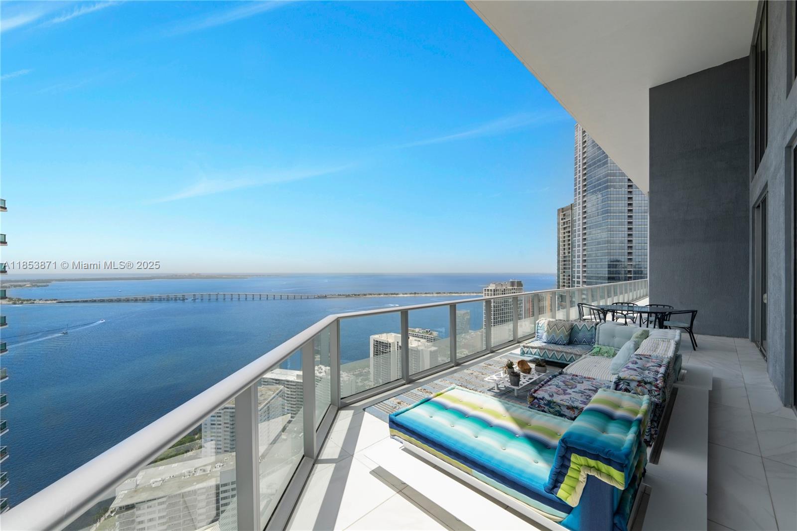 A high-rise balcony features outdoor furniture overlooking a bay and a distant bridge — 1300 Brickell Bay Dr # 4401, Miami FL 33131, MIAMI, FL