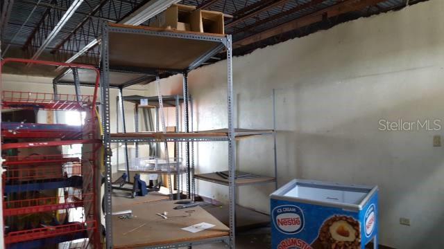 A storage room features metal shelving units and a Nestle ice cream freezer — Gautier Benitez INT. JIMENEZ SICARDO, CAGUAS, PR
