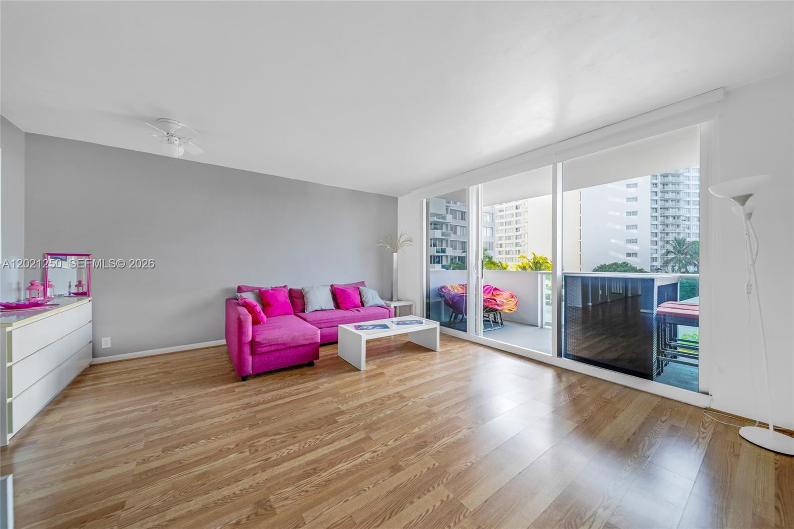 A living room features a pink sectional sofa, wood-look flooring, and a balcony with views — 1200 West Ave # 327, Miami Beach FL 33139, MIAMI BEACH, FL