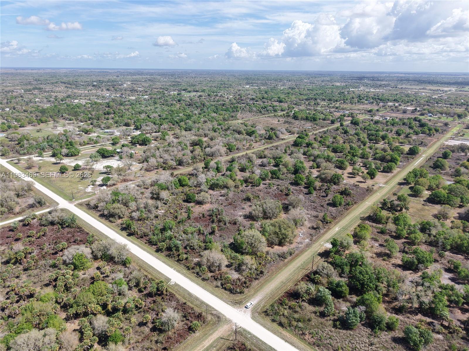 An aerial view shows a rural landscape with dirt roads intersecting through wooded, undeveloped land — 20755 NW 262ND, Okeechobee FL 34972, OKEECHOBEE, FL