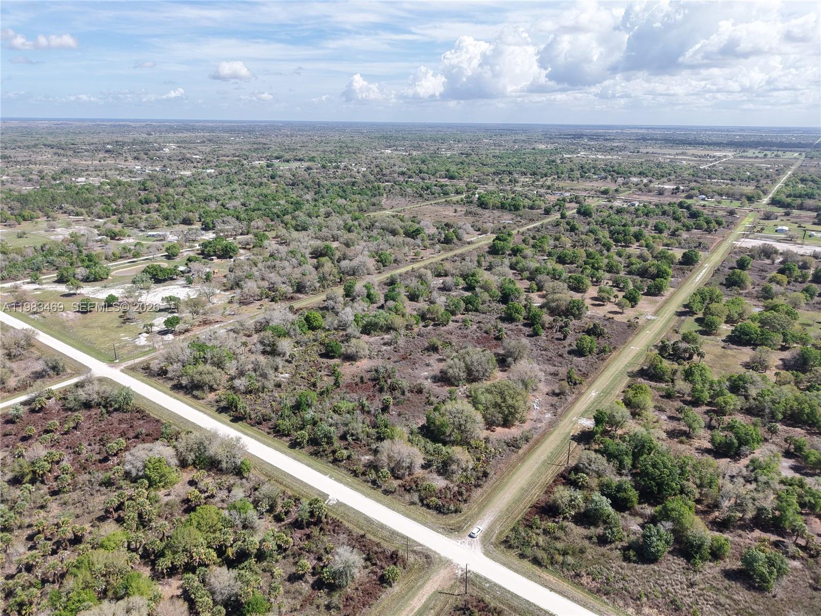 An aerial view shows a rural landscape with dirt roads intersecting through wooded land — 20755 NW 262ND, Okeechobee FL 34972, OKEECHOBEE, FL