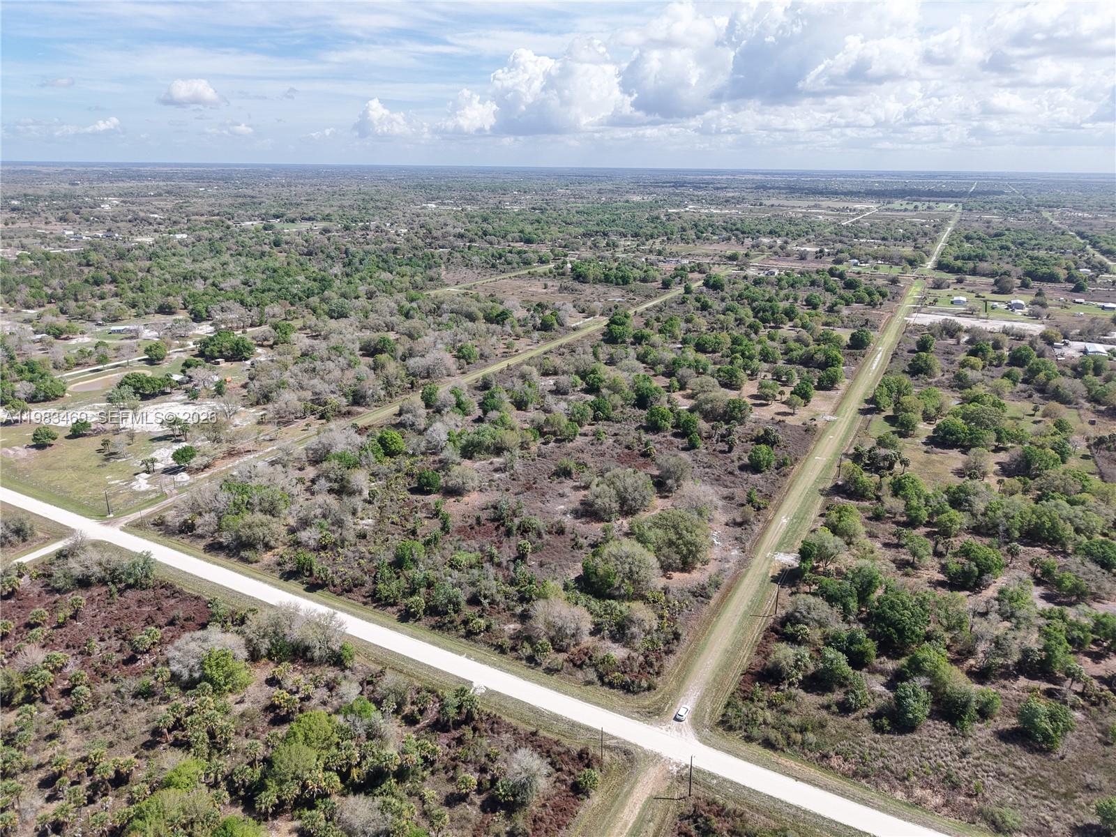 An aerial view shows a rural landscape with dirt roads intersecting through wooded lots — 20755 NW 262ND, Okeechobee FL 34972, OKEECHOBEE, FL