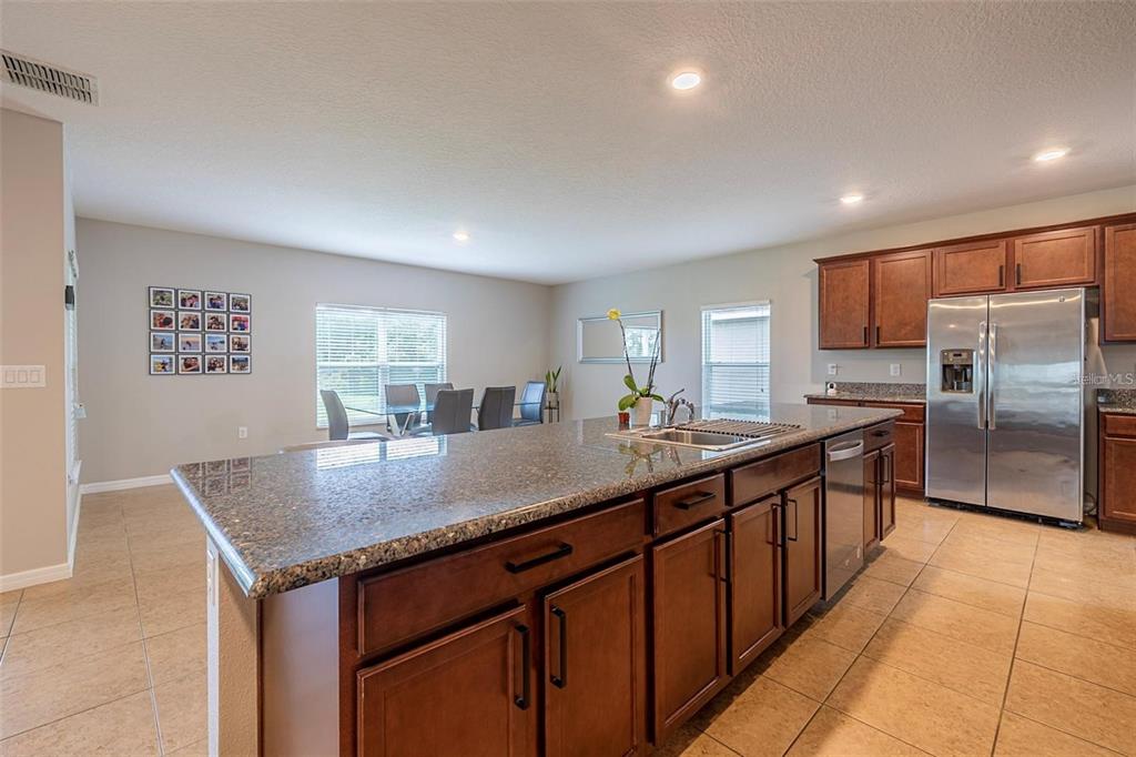 A kitchen with a large granite-topped island, dark wood cabinets, and stainless steel appliances — 565 OGELTHORPE DRIVE, DAVENPORT, FL