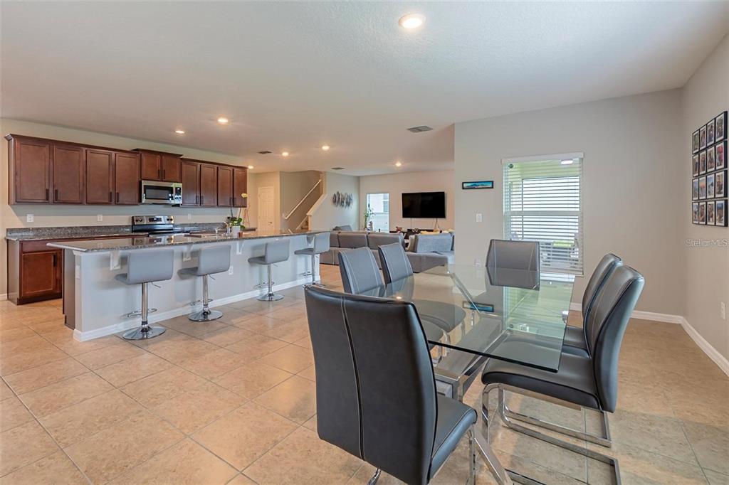 An open-concept kitchen with dark wood cabinets and a dining area with a glass table — 565 OGELTHORPE DRIVE, DAVENPORT, FL