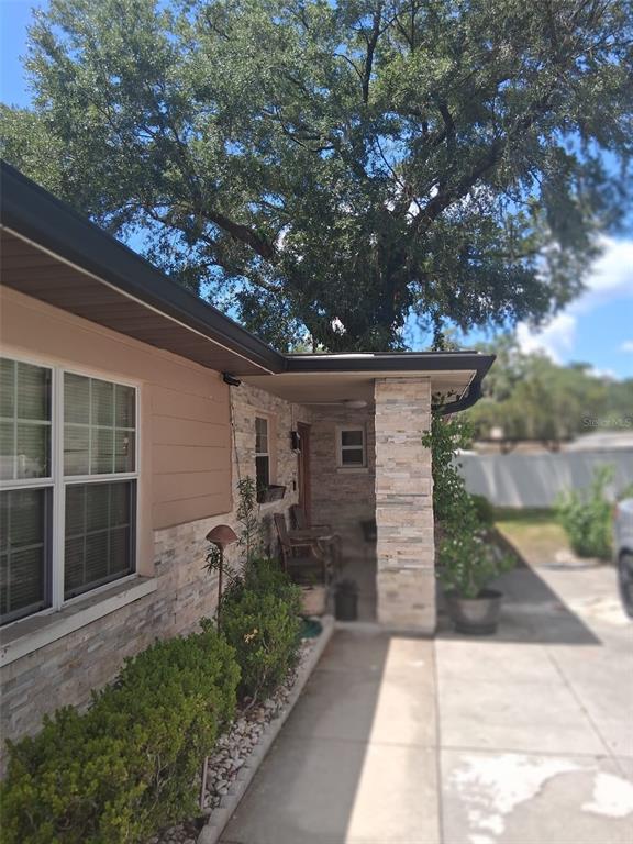 A stone-accented house exterior features a covered front porch, a concrete walkway, and landscaping — 702 COULTER PLACE, BRANDON, FL