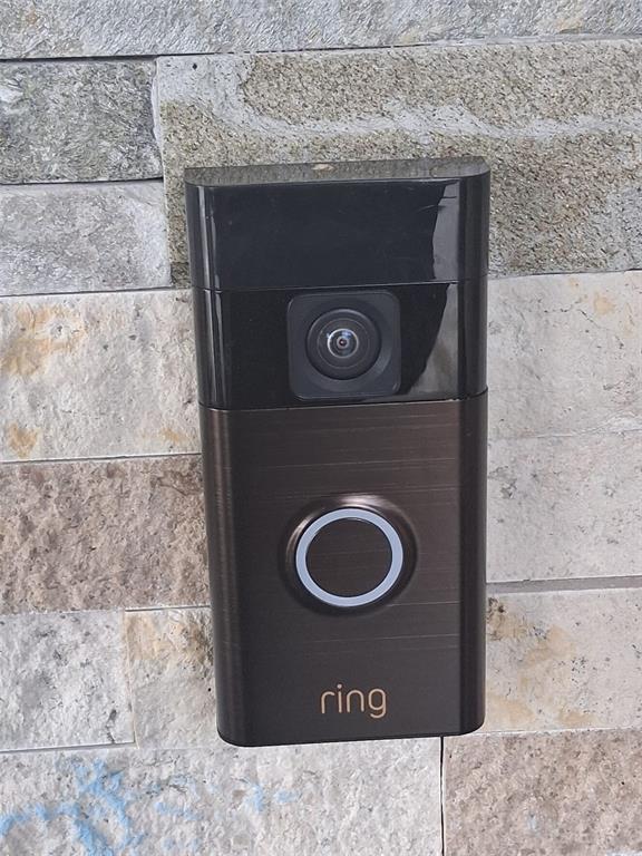 A bronze-colored Ring video doorbell is mounted on a textured stone wall — 702 COULTER PLACE, BRANDON, FL