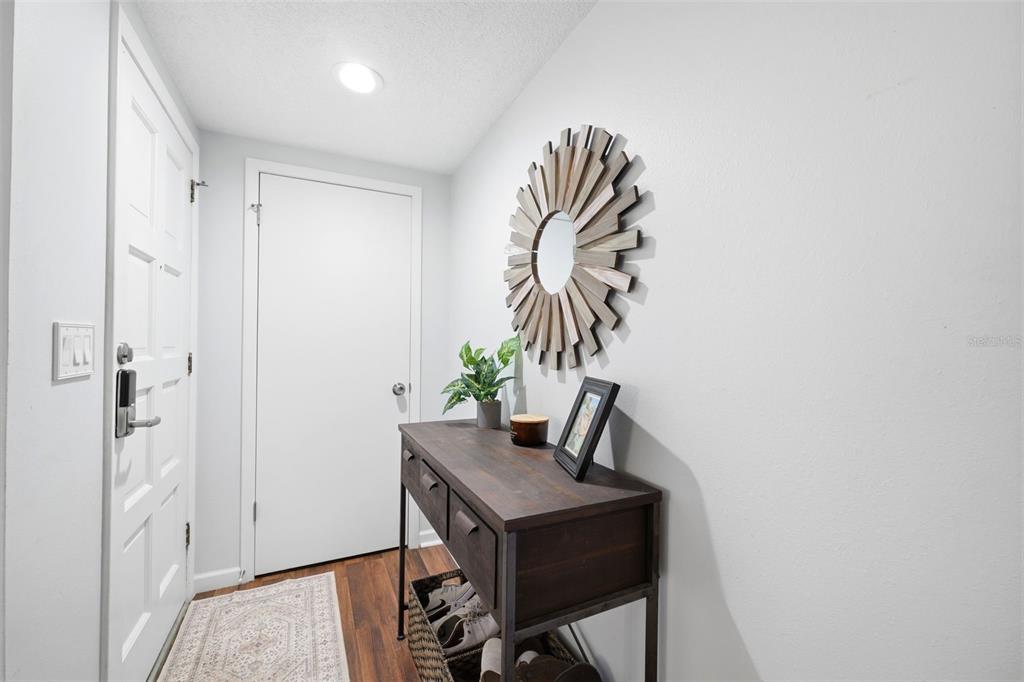 An entryway features a dark wood console table, a sunburst mirror, and a white door — 12408 STAGECOACH LANE, HUDSON, FL