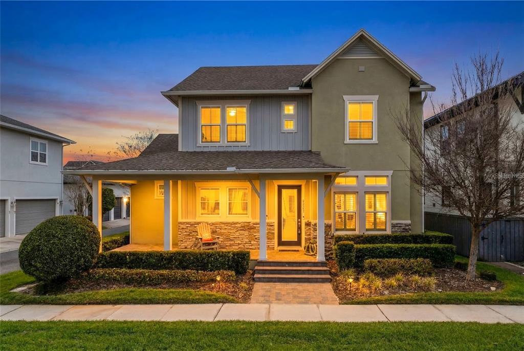 A two-story house with a front porch, stone accents, and a landscaped yard at dusk — 8539 MARTINSON STREET, ORLANDO, FL