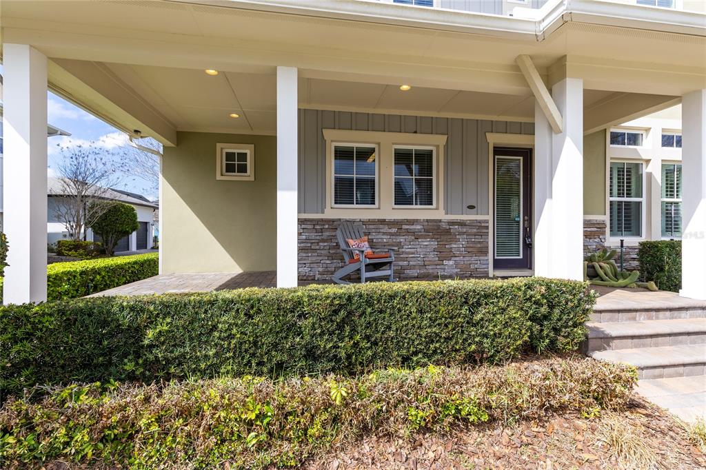 A covered front porch features a stone facade, a rocking chair, and a glass-paneled door — 8539 MARTINSON STREET, ORLANDO, FL